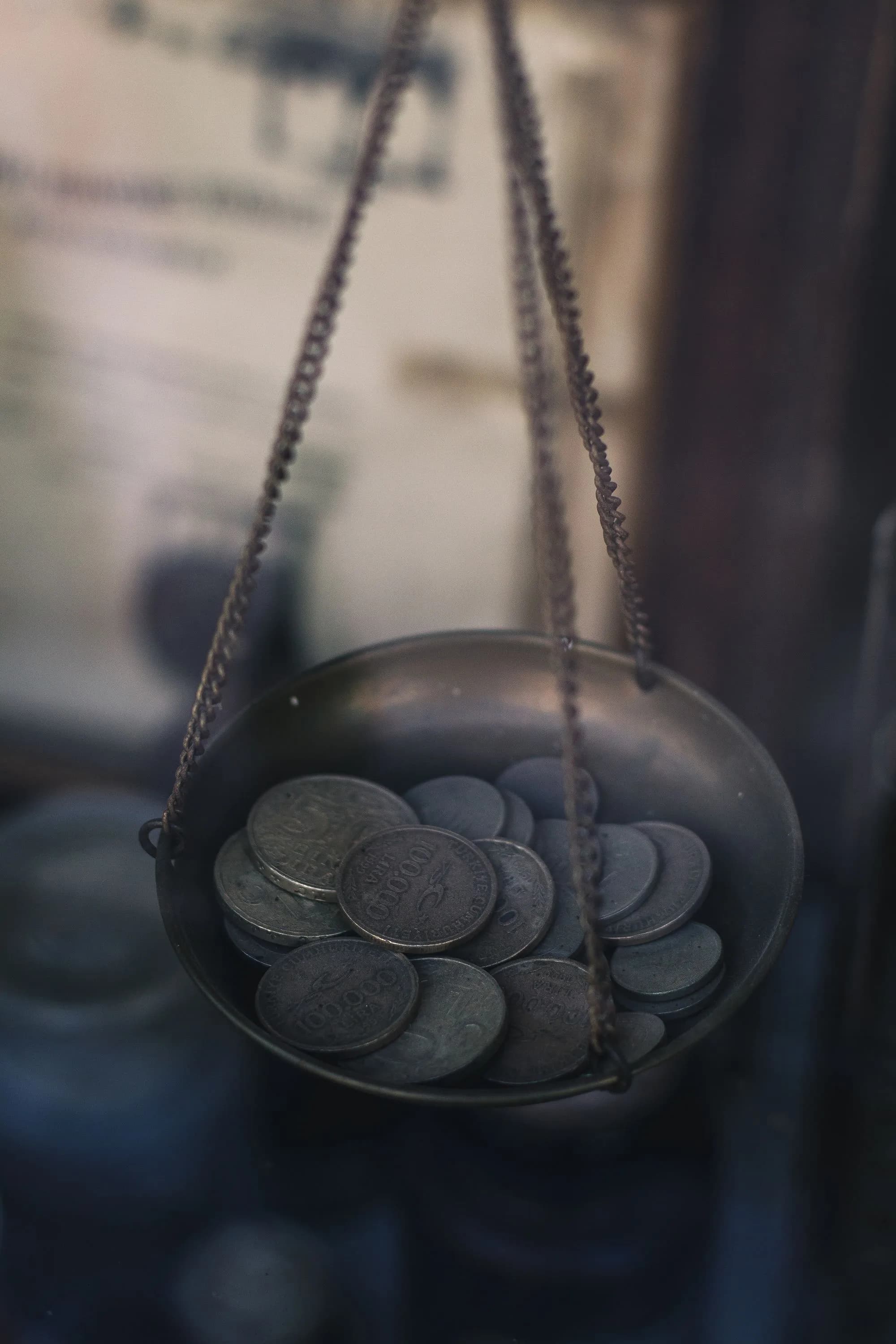 Old coins resting in the pan of an antique hanging balance scale