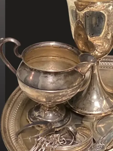 A tarnished sterling silver tea service with chains draped over the tray